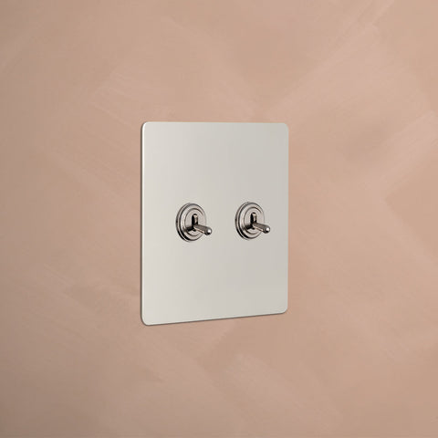 Minimalist light  switch panel with two round toggles on a smooth peach-colored wall.