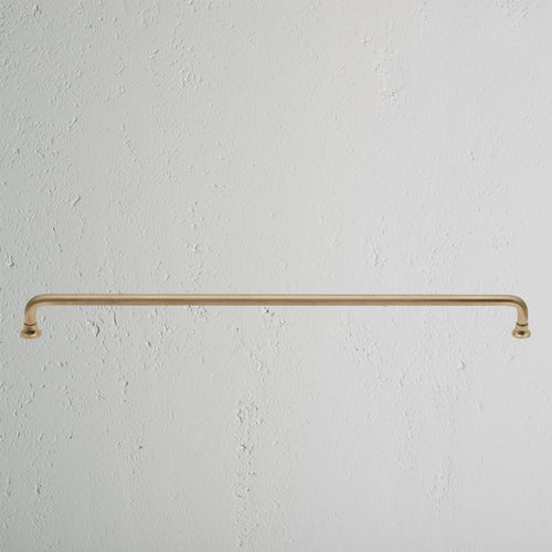 Large antique brass Sycamore furniture handle mounted horizontally on a white textured surface.