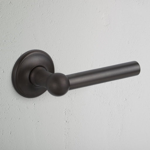 Harper Dummy Door Handle Set in bronze finish, shown mounted on a light textured wall.