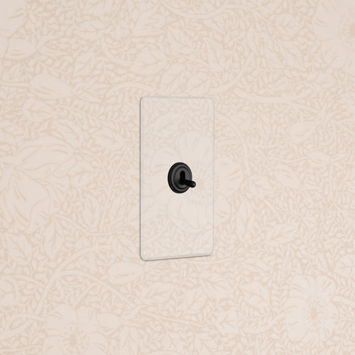 Kew 1G Toggle Switch with a clear bronze cover plate, mounted on a beige wall with a floral pattern.