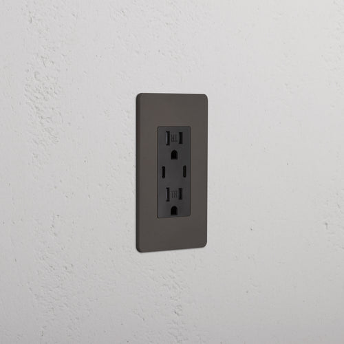 Grove 1G 15A USB Outlet in bronze black finish with two sockets, mounted on a white textured wall.