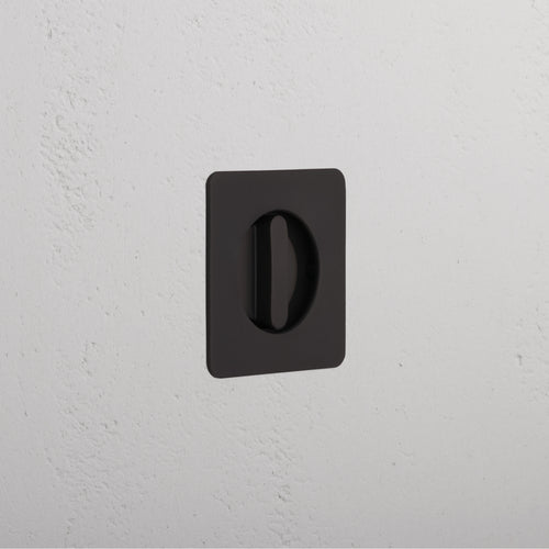 Regent Recessed Thumbturn in bronze finish, mounted on a white textured wall, featuring a central oval cutout.