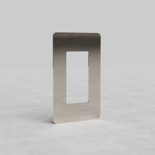 1-gang outlet plate Kew US in polished nickel, with large rectangular cutout, on light surface.