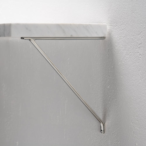Polished nickel Brixton Shelf Bracket Medium with modern triangular design, mounted to a white wall.