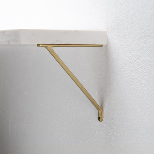 Small Brixton Shelf Bracket in Antique Brass finish, mounted on a white wall for supporting shelves.