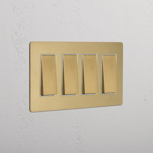 Kew 4G Rocker Switch in antique brass with white inserts, shown mounted on a wall.