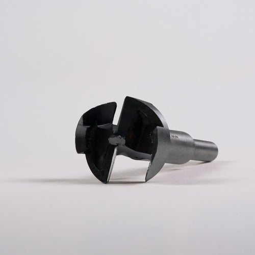 Close-up of a metal Door Handle Installation Drill Bit with sharp, circular cutting edges on a gray surface.