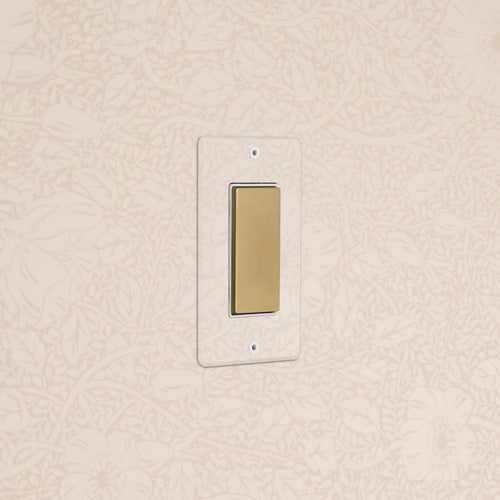 Kew 1G Center Retractive Rocker Switch in clear antique brass with white insert, wall-mounted.