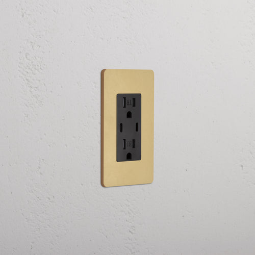 Grove 1G 15A USB Outlet in black with an antique brass faceplate, installed on a wall.