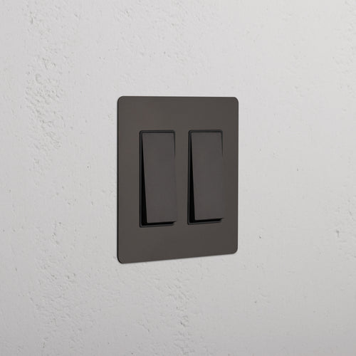 Kew 2G Rocker Switch in Bronze Black finish, both switches off, shown on a white textured wall.