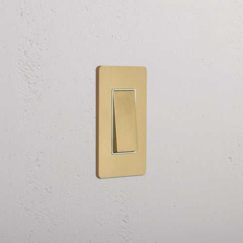 Grove 1G Retractive Rocker Switch in antique brass white with a rectangular plate, mounted on a wall.