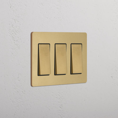 Grove 3G Rocker Switch in Antique Brass Black finish, shown with three switches on a white wall.