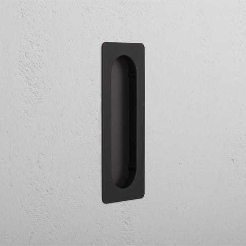 Rectangular Regent Recessed Medium Pull in bronze finish, installed on a white textured wall.