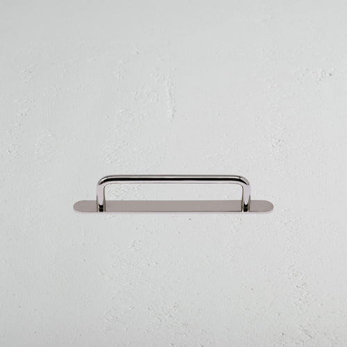 Kilburn Furniture Handle Small in polished nickel, mounted horizontally on a white textured wall.