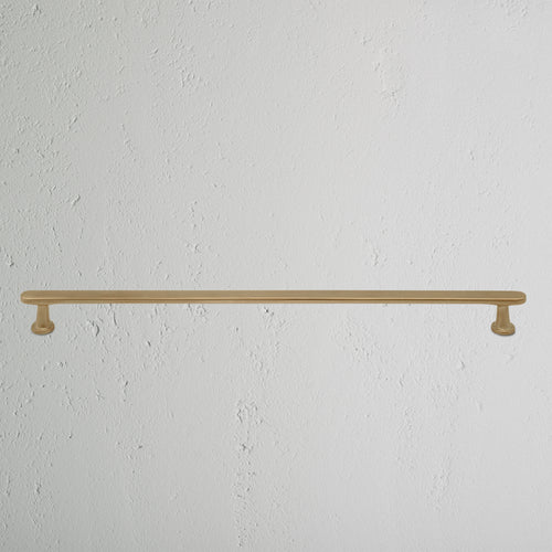 Large antique brass Milliner furniture handle with a straight, simple design mounted on a white surface.