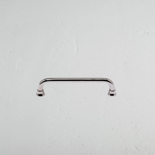 Sycamore Furniture Handle Small in polished nickel, featuring curved edges, mounted on a white surface.