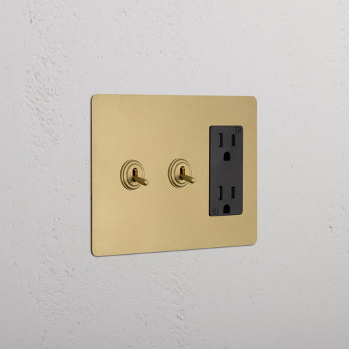 Kew 3G 2x Toggle Switch & Outlet in Antique Brass Black with two toggles and black outlet on wall plate.