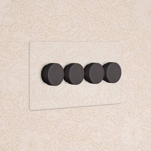 Kew 4G Dimmer Switch - Clear Bronze with four black round dimmer knobs on a clear glass wall plate.