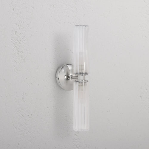 Claremont Medium Wall Light with fluted glass shade and polished nickel base, mounted on a white wall.