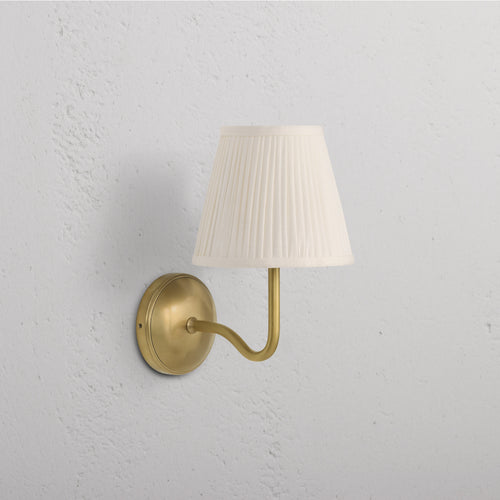 Malvern Medium Wall Light in Alabaster White with antique brass base and arm, white pleated shade.