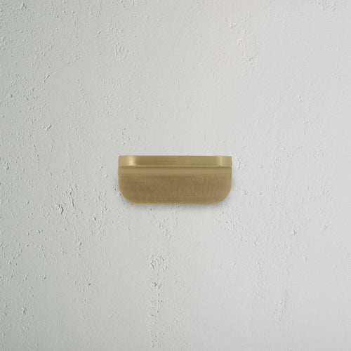 An extra small Oxford furniture handle in antique brass finish, mounted on a white surface.