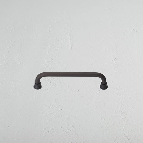 Sycamore Furniture Handle Small in bronze finish, featuring rounded ends, mounted on a light wall.