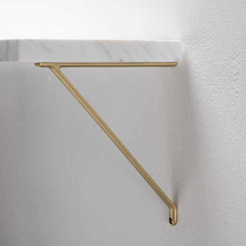 Medium-sized Brixton Shelf Bracket in antique brass, mounted on a white wall and supporting a shelf.