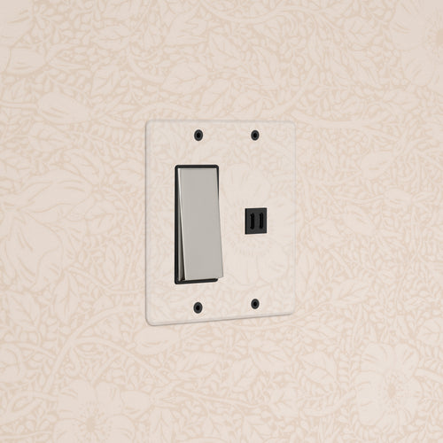 Clear polished nickel black Kew 2G rocker switch with fast charge USB on a wall against beige floral wallpaper.