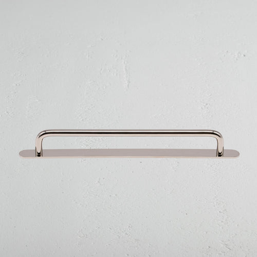 Kilburn Furniture Handle Medium in polished nickel, mounted horizontally on a white textured surface.