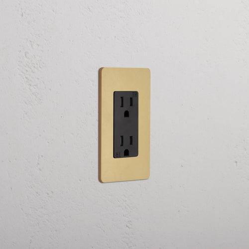 Grove 1G 15A electrical outlet with an antique brass black faceplate, shown installed on a wall.