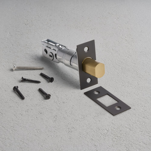 Bronze tubular privacy deadbolt set with latch, strike plate, and mounting screws on gray background.