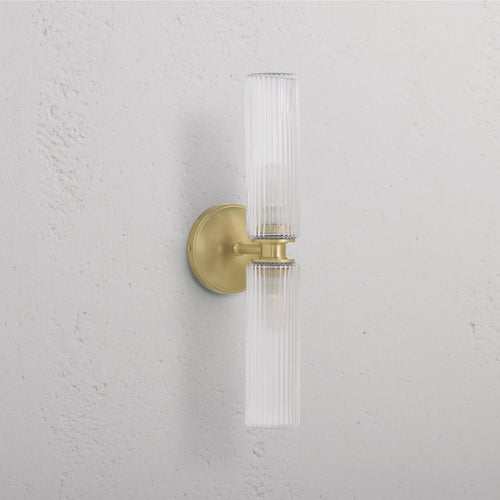 Claremont Medium Wall Light with fluted glass and antique brass base, featuring two ribbed glass cylinder shades.