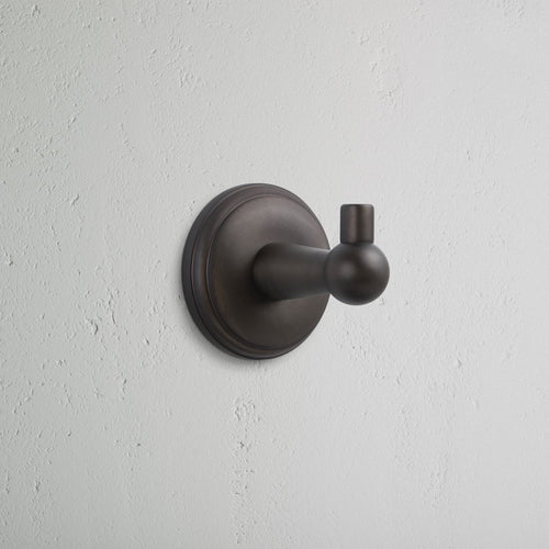 Hyde Hook in dark bronze finish with rounded design and circular base, mounted on a white wall.