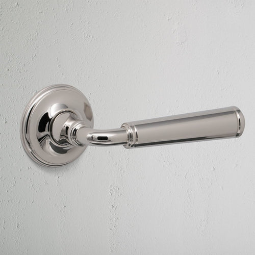 Close-up of Digby Passage Door Handle Unsprung in polished nickel finish, mounted on a white wall.