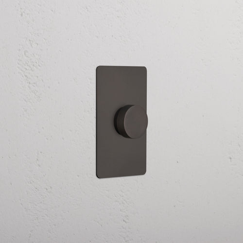 Bronze Kew 1G Dimmer Switch with a rectangular plate mounted on a white textured wall.