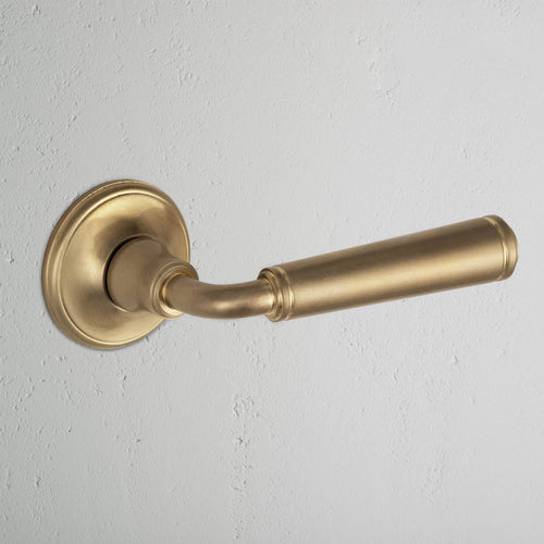 Digby Passage Door Handle Set in antique brass with a brushed finish, mounted on a round base plate.