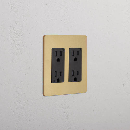 Grove 2G Outlet in Antique Brass Black finish with two black sockets, mounted on a white textured wall.