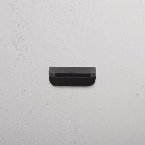 Bronze Oxford Furniture Handle Extra Small, rectangular with rounded edges, mounted on a white wall.