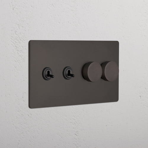 Bronze Grove 4G switch plate with two toggle switches and two dimmer knobs, mounted on a white wall.
