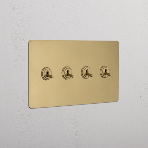 Kew 4G Toggle Switch in antique brass with a matte metallic finish, mounted on a white wall.