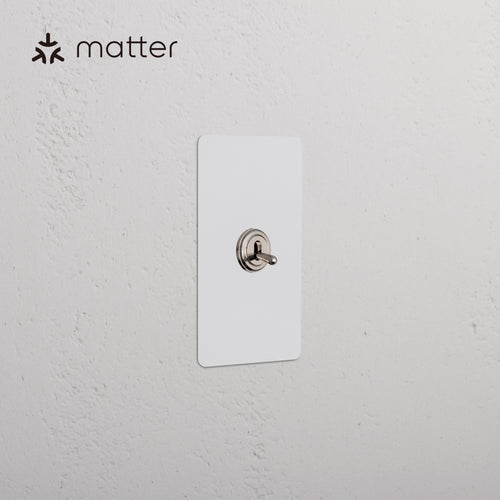 Kew 1G Smart Retractive Toggle Switch in paintable polished nickel, shown mounted on a white wall.