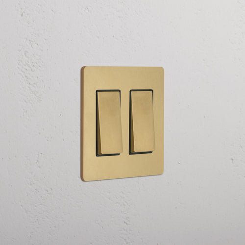 Grove 2G Rocker Switch in Antique Brass Black finish, featuring two rectangular switches on a wall.