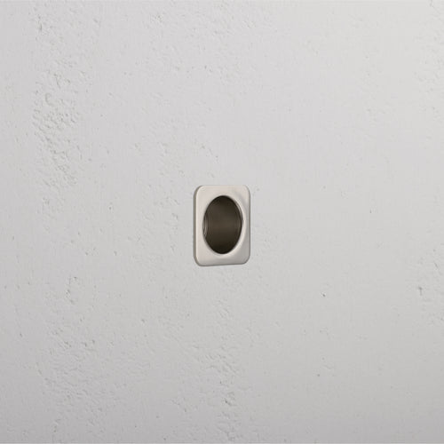 Close-up of a Regent Recessed Edge Pull in polished nickel, installed on a flat surface for cabinet or drawer use.