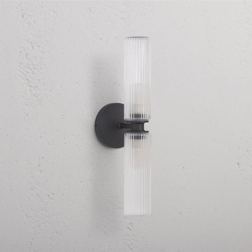 Claremont Medium Wall Light with fluted glass shades and bronze finish, mounted on a white wall.