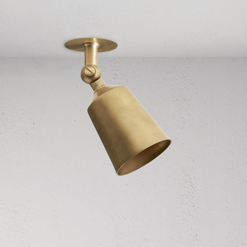 Perryn Single 50mm Spotlight in antique brass with a cone-shaped shade, angled downward on a ceiling mount.