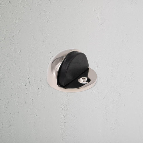 Clifton Half Moon Door Stop in polished nickel, mounted on wall to protect surfaces from door impact.