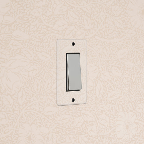 Kew 1G Rocker Switch in clear polished nickel black finish, installed on floral-patterned cream wall.