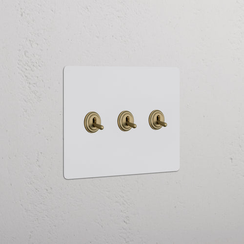 Kew 3G Toggle Switch - Paintable Antique Brass with three horizontally aligned toggles on a rectangular plate.