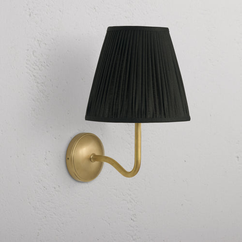 Large Malvern Wall Light in deep green with antique brass curved arm and round base, mounted on a white wall.