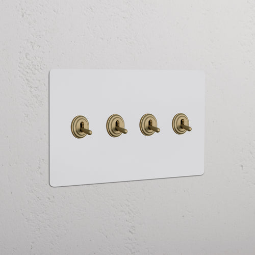 Kew 4G Toggle Switch with four paintable antique brass toggles on a white wall plate, shown installed.